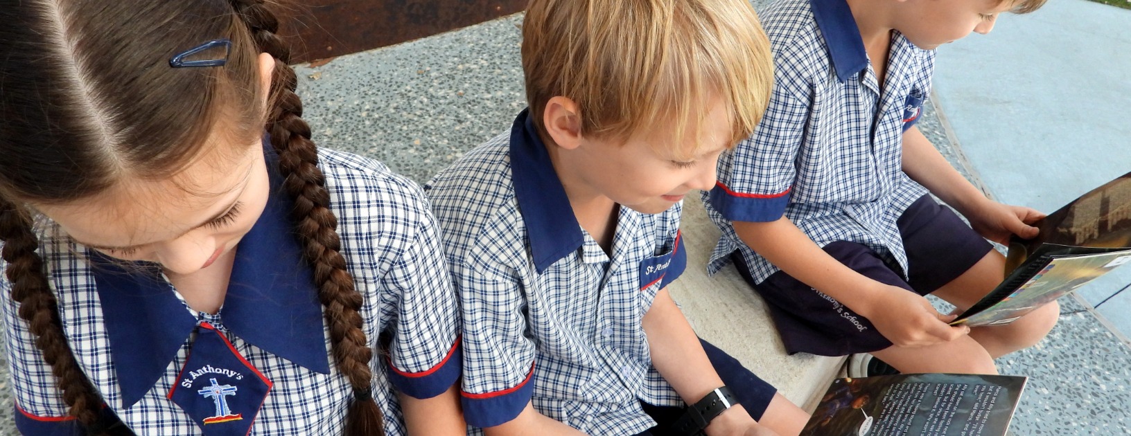 Students in school uniform reading books together outdoors, highlighting shared learning and literacy engagement Provide your feedback on BizChat